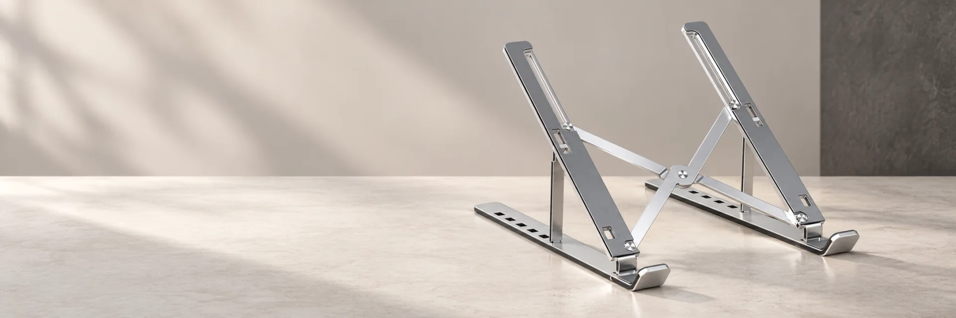 Giá đỡ laptop nhôm bạc trên nền bàn studio sáng